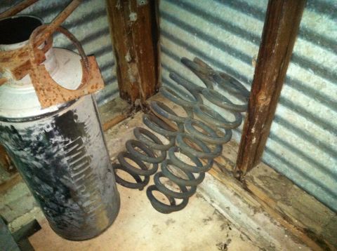 1986 Ford Bronco - Coil springs and a metal container are stored in a corner with corrugated metal walls.