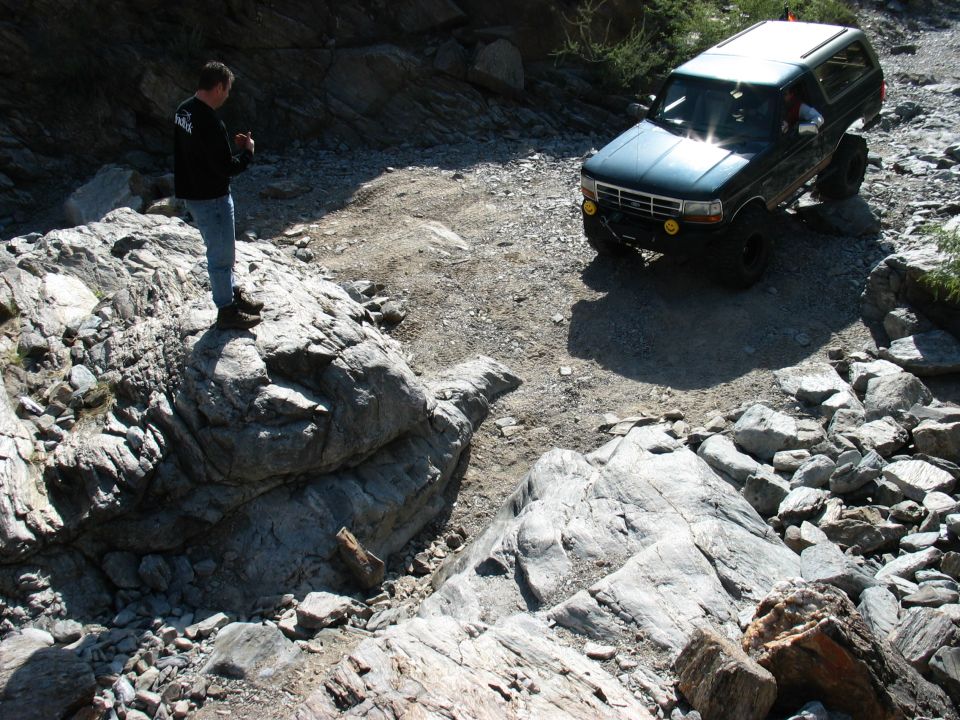 Green lifted Ford Bronco SUV parked in a rocky trail wash