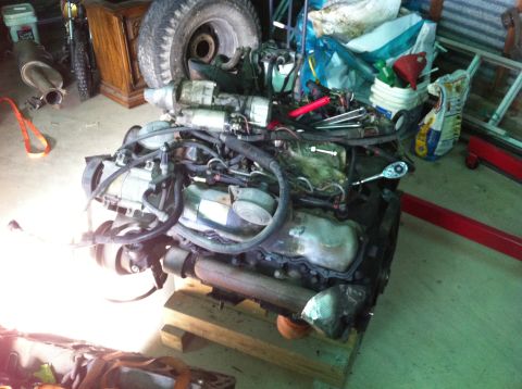 1986 Ford Bronco - Engine removed from vehicle, resting on wooden blocks in a garage setting.