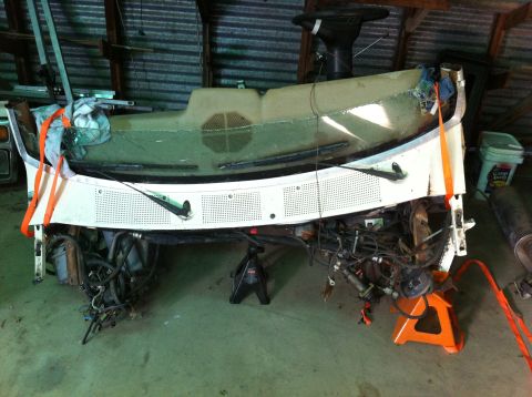 1986 Ford Bronco - Disassembled vehicle front end and dashboard assembly supported by jack stands in a workshop.