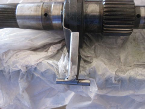1994 Ford Bronco - Close-up view of a transfer case component, likely a shaft or gear, with a welded metal bracket attached.
