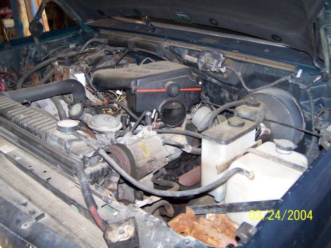 1986 Ford Bronco - The engine bay of a vehicle is shown, with various components and hoses visible. A date stamp indicates the photo was taken on 03/24/2004.