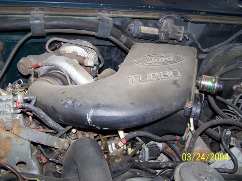 1986 Ford Bronco - Close-up of a dusty Ford turbo intake pipe, showing the brand and model designation.