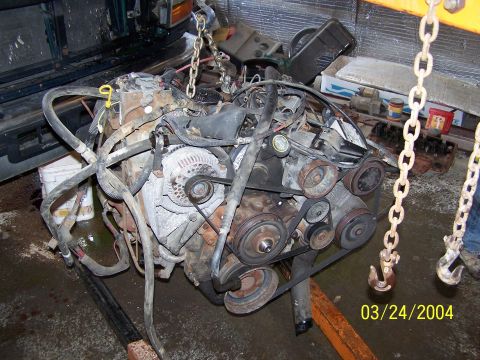 1986 Ford Bronco - Engine removed from a vehicle, suspended by chains with a date stamp of March 24, 2004.