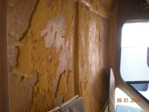 1986 Ford Bronco - The interior of a vehicle shows significant damage to the paneling, with foam peeling away.