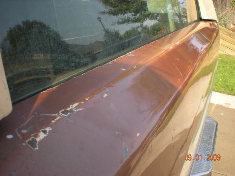 1986 Ford Bronco - The rear of a brown SUV shows significant paint damage and wear.