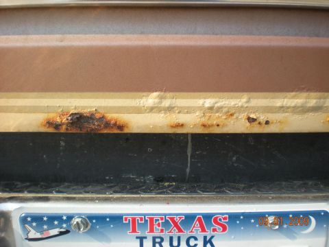 1986 Ford Bronco - Rust damage is visible on the lower body panel of a vehicle, with a Texas license plate below.