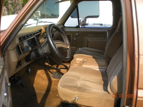 1986 Ford Bronco - Interior view of a 1986 Ford Bronco, highlighting its brown upholstery and dashboard details.