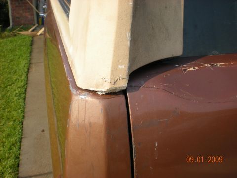 1986 Ford Bronco - Close-up of a brown vehicle's rear quarter panel and trim, revealing wear and tear.