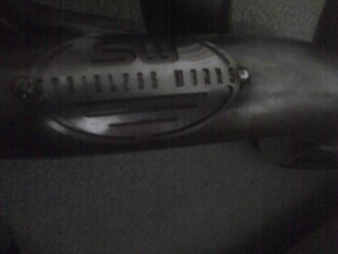 2003 Ford Crown Victoria - Close-up of a stainless steel exhaust pipe a circular emblem with 'STAINLESS WORKS' text.