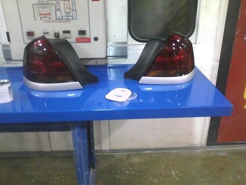 2003 Ford Crown Victoria - Pair of car tail lights displayed on a blue table in a workshop setting.