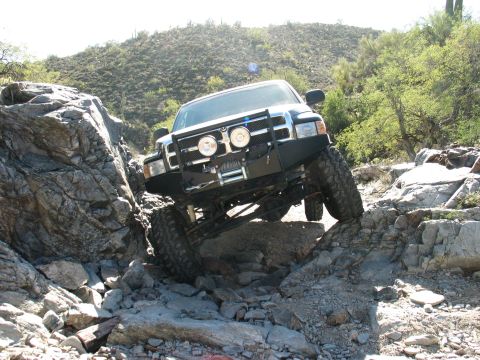 1994 Ford Bronco - This modified truck navigates a challenging rocky terrain, its off-road capabilities.