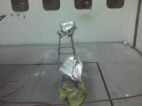 2003 Ford Crown Victoria - A car fender is suspended and covered in protective material inside a paint booth.