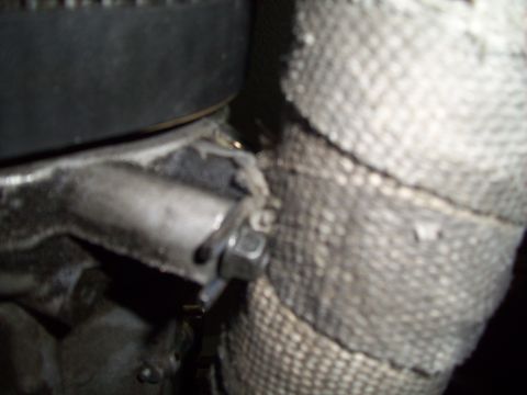 1995 Ford Probe - A close-up view of an engine component wrapped in heat-resistant material, secured with a bolt.