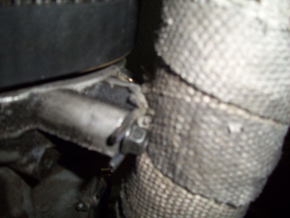 Close-up of engine part with heat wrap and a bolt