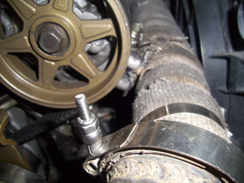 Close-up of a gold pulley and a hose wrapped in heat shielding with a hose clamp