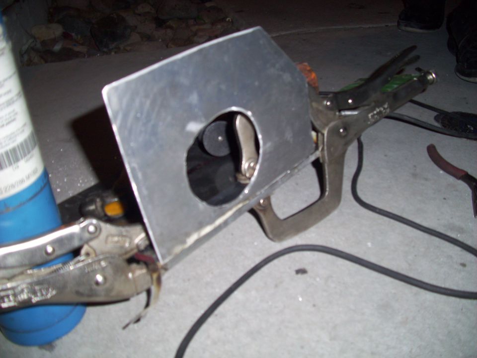 Metal plate with hole clamped to pipe, with propane torch and tools nearby