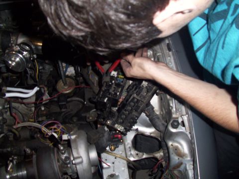 1995 Ford Probe - A person works on the fuse box in a vehicle's engine bay, which includes a turbocharger.