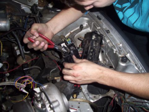 1995 Ford Probe - A person works on the fuse box and wiring in a vehicle's engine bay.
