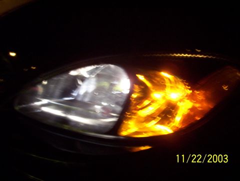 2003 Ford Taurus - Close-up of the front headlight and amber turn signal assembly on a 2003 Ford Taurus.