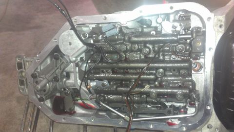 1973 Chevrolet Camaro - The internal components of an automatic transmission valve body are exposed, showing intricate mechanical parts and wiring.