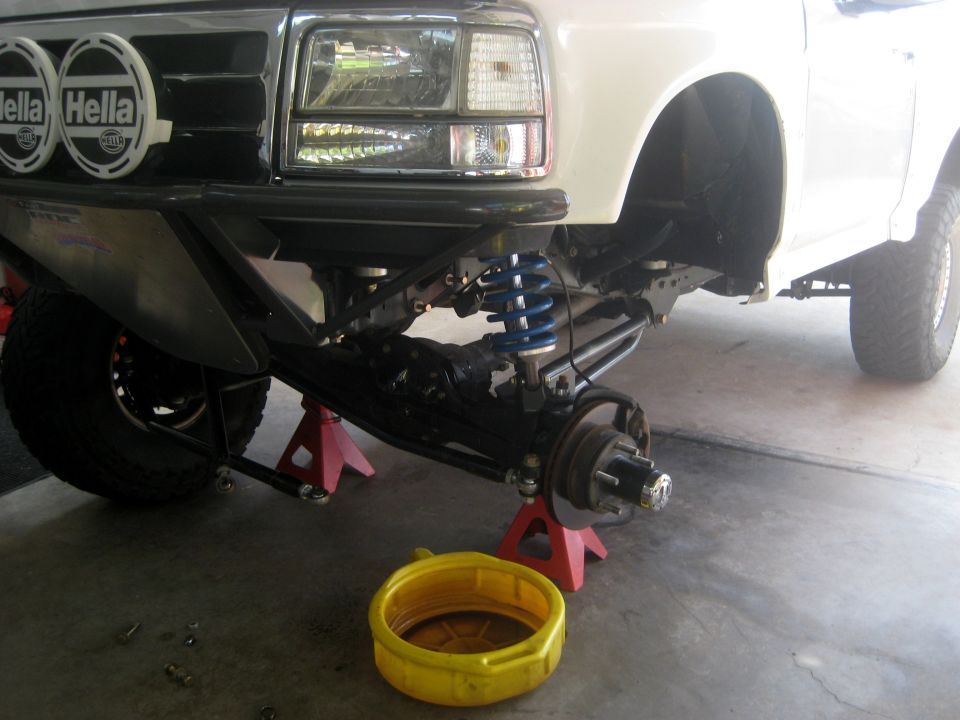 Front suspension of white SUV with aftermarket bumper and Hella lights