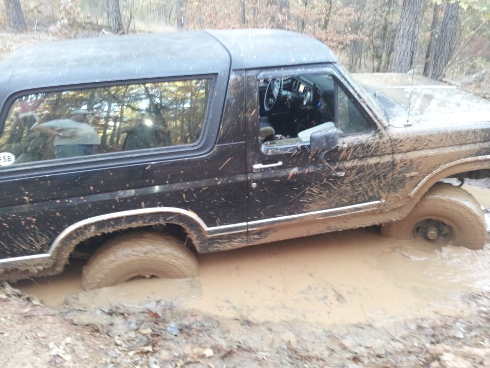 Black 1986 Ford Bronco stuck in mud