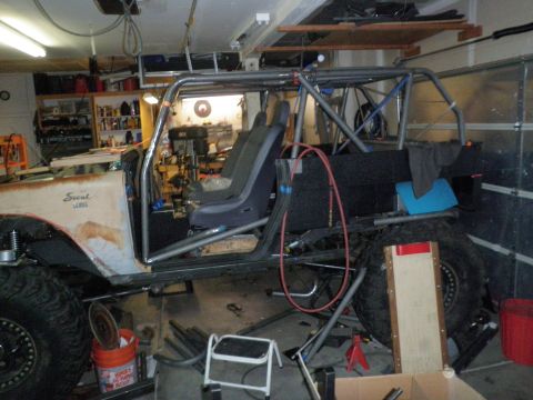 1961 International Scout 800 - A 1961 International Scout is modified with a full roll cage and racing seats inside a garage.
