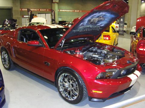2007 Ford Mustang - A red Ford Mustang with white racing stripes is displayed with its hood open, revealing the engine and custom artwork.