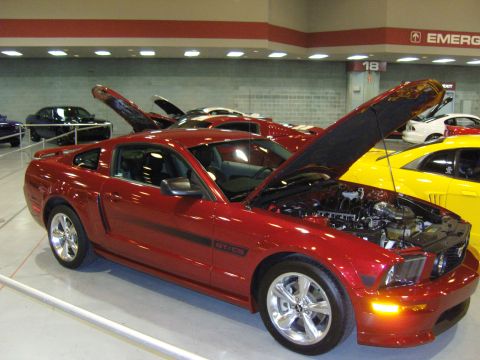 2007 Ford Mustang - Red 2007 Ford Mustang GT/CS on display with its hood open, surrounded by other vehicles.