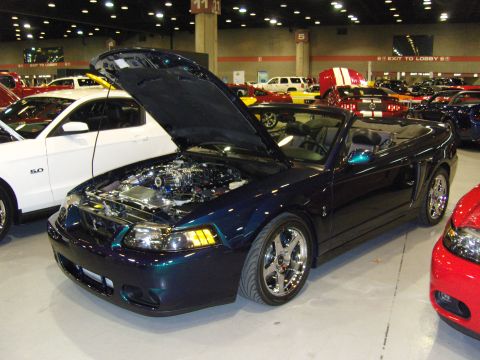2007 Ford Mustang - A dark blue convertible Mustang is displayed with its hood open, revealing the engine bay. Another Mustang is parked beside it.