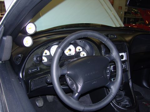 2007 Ford Mustang - Interior view of a car's dashboard, a steering wheel with a COBRA emblem and additional gauges.