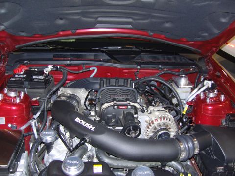 2007 Ford Mustang - The engine bay features a Roush supercharger and intake system on a red vehicle.