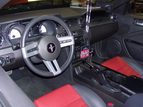 2007 Ford Mustang - The interior of a car shows red and black seats and a Roush tag, suggesting a modified vehicle.