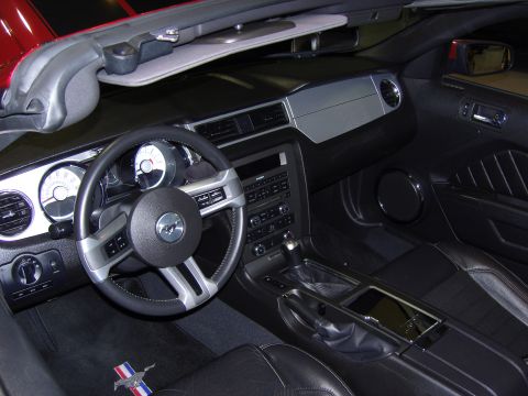 2007 Ford Mustang - The interior of a black convertible shows a detailed dashboard and steering wheel, with a Mustang emblem on the floor mat.