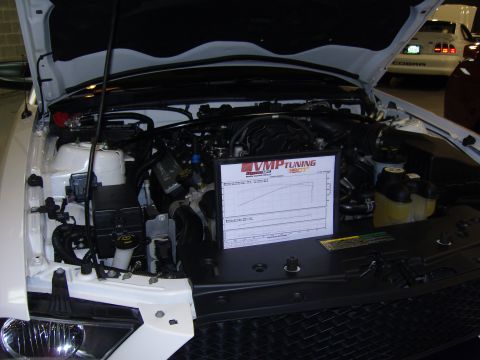 2007 Ford Mustang - A dyno chart is placed in the engine bay of a white vehicle, with another car visible in the background.
