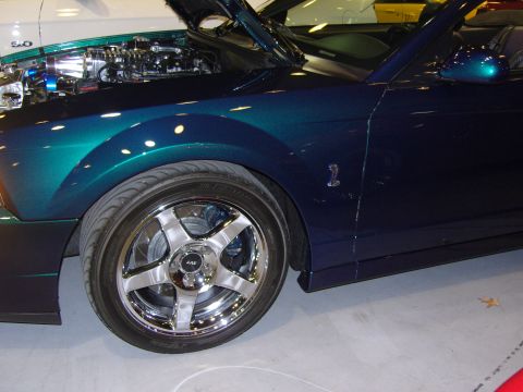 2007 Ford Mustang - A dark teal Ford Mustang convertible is displayed with its hood open, revealing the engine and custom wheels.