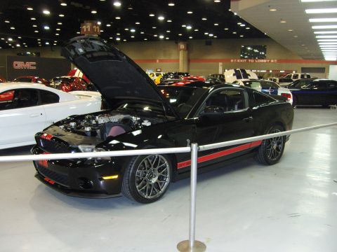 2007 Ford Mustang - Black 2007 Ford Mustang GT with red racing stripes displayed at a car show.