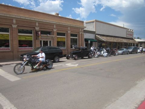 1991 Ford LTD Crown Victoria - A street scene with a motorcycle in the foreground and several cars and motorcycles parked along the side of the road.
