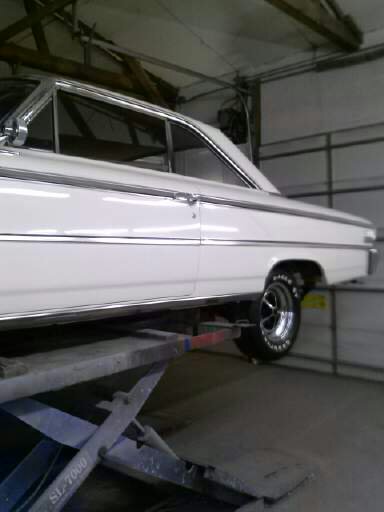1960 Ford Falcon - Side view of a white 1963 Ford Galaxie on a car lift inside a garage.