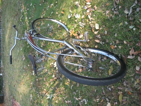 1994 Ford Bronco - A vintage-style bicycle with chrome accents and a leather seat rests on a grassy lawn scattered with autumn leaves.