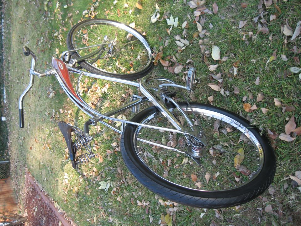 Vintage bicycle with chrome frame and red tank lying on grass with fallen leaves