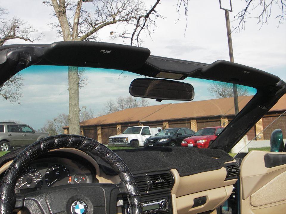 Interior of a top-down BMW roadster showing tan trim, gauges and windshield frame