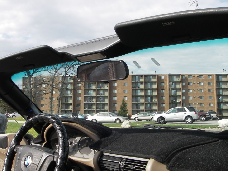 Passenger-side interior view of a top-down BMW roadster with tan dash and visors