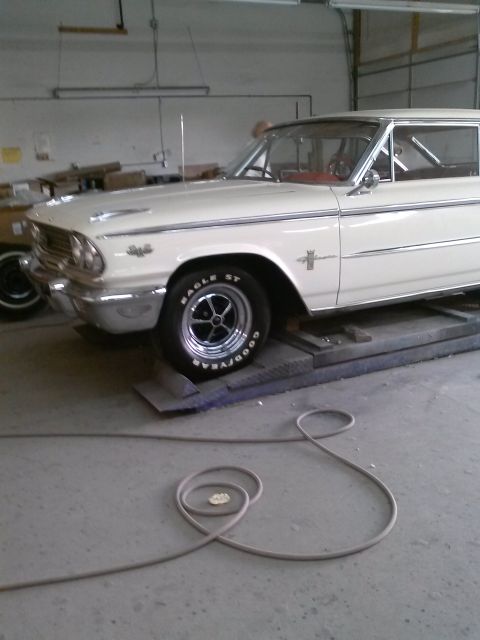 1960 Ford Falcon - White 1961 Ford Falcon in a garage, raised on a lift with a coiled hose on the floor.
