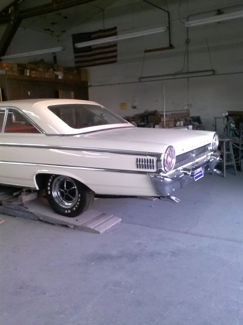 1960 Ford Falcon - The rear of a white 1961 Ford Galaxie is shown in a garage setting with an American flag on the wall.