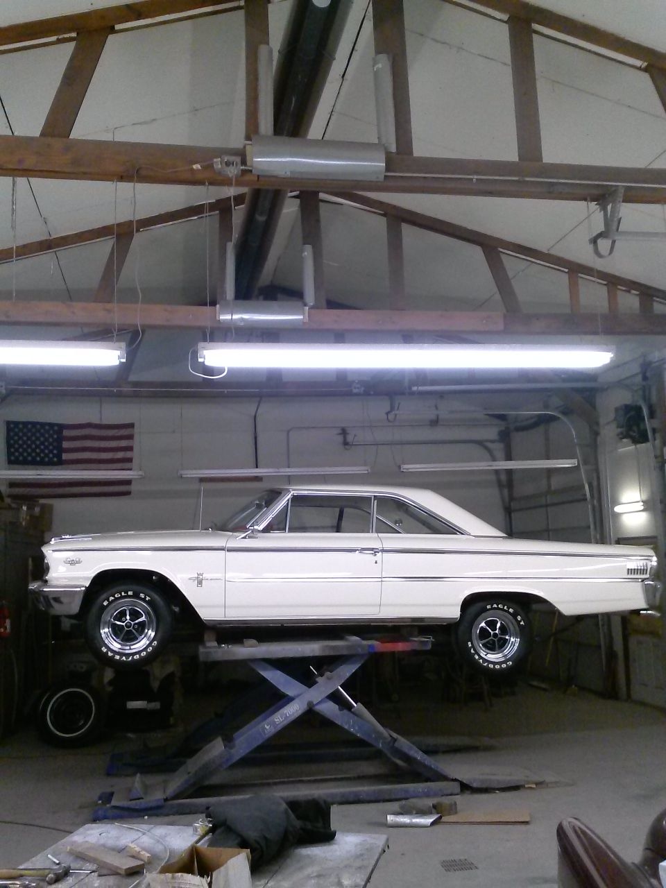 White 1963 Ford Galaxie coupe on a car lift, side view