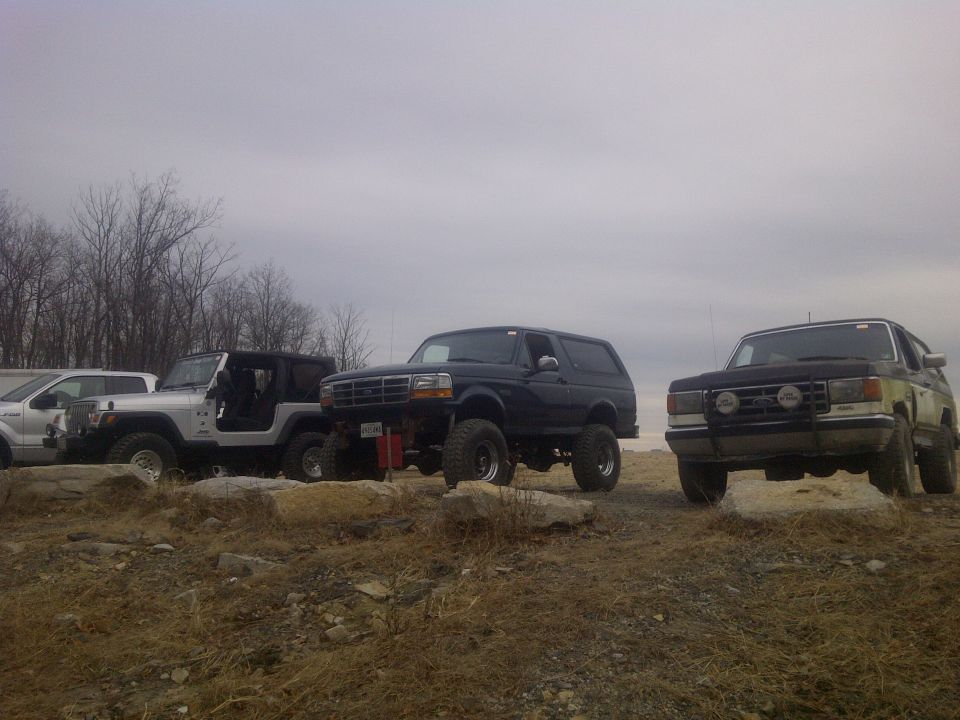 Dark blue 1995 Ford Bronco parked on rocky terrain with other vehicles