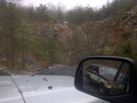 1995 Ford Bronco - View of a 1995 Ford Bronco in the side mirror, with a rocky, wooded landscape in the background.
