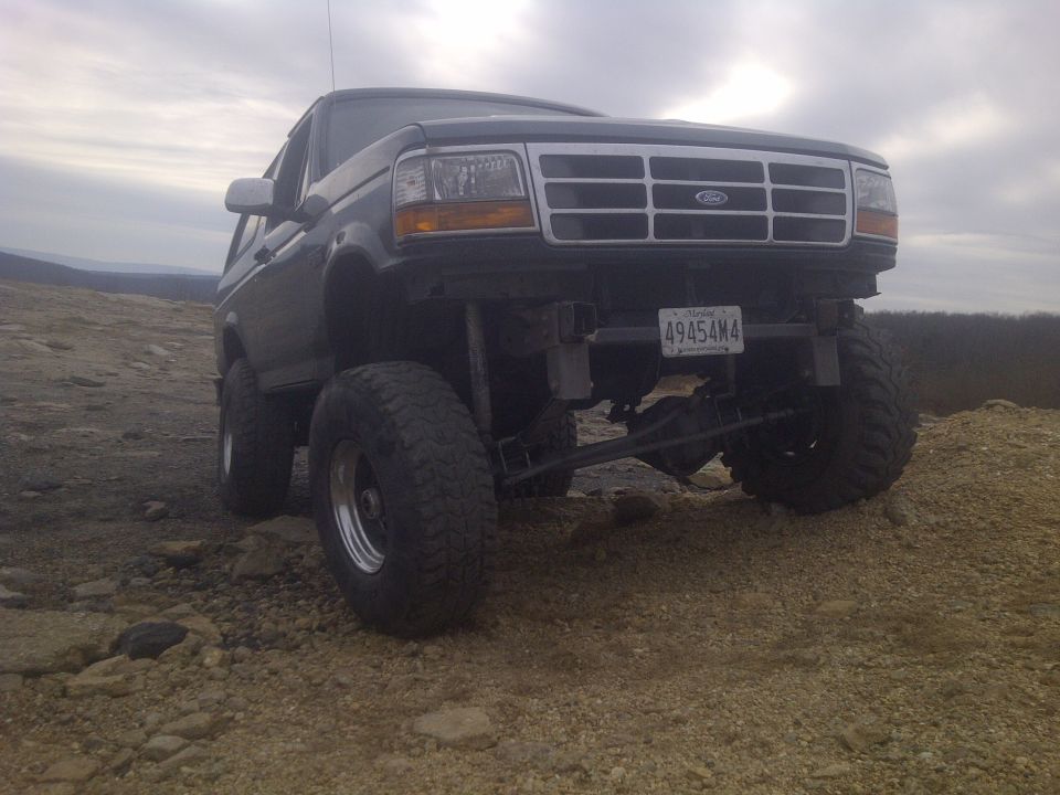 Lifted Ford Bronco on rocky terrain, front view. License plate reads 49454M4